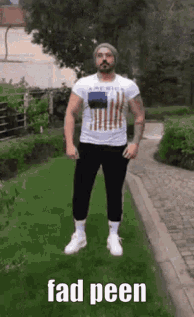 a man wearing a white shirt with an american flag on it is standing on a path .