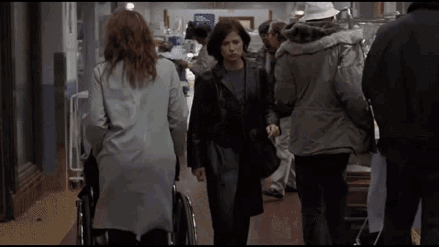 a woman in a wheelchair is walking in a hallway with other people