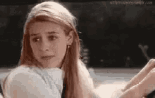 a woman with long blonde hair is sitting in a car and looking at the camera .