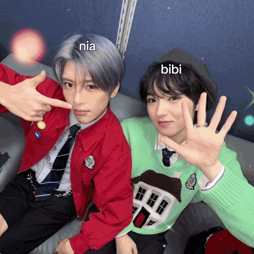 two young men are posing for a picture and one of them is wearing a green sweater and the other is wearing a red jacket and tie