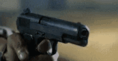 a person is holding a gun in their hand in a blurry photo .