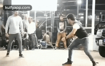 a group of men are standing next to each other on a dance floor in front of a car .