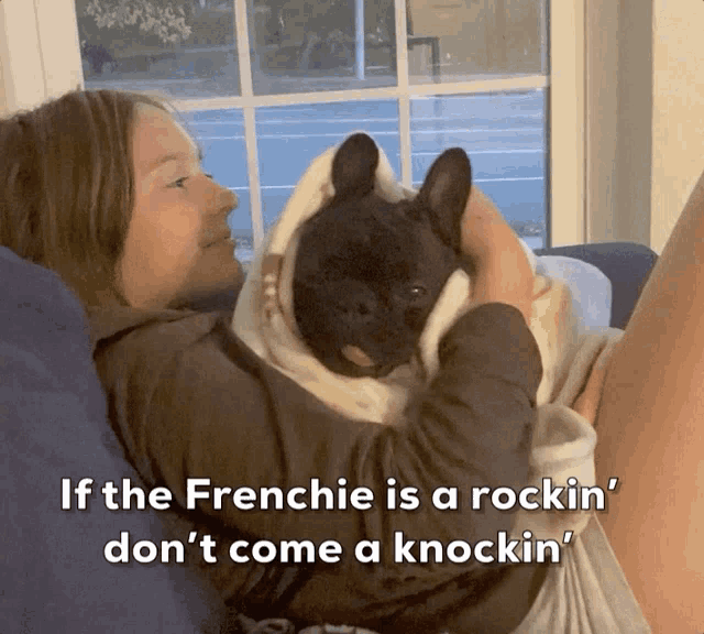 a woman is laying on a couch holding a french bulldog with the caption if the frenchie is a rockin