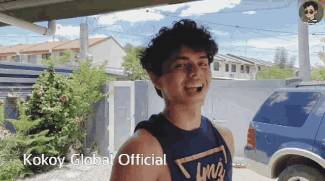 a young man wearing a blue tank top with the words kokoy global official on the bottom