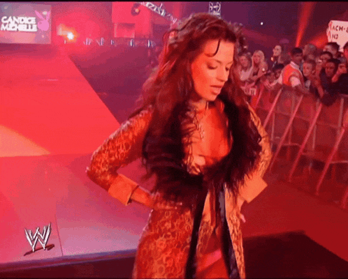 a woman in a leopard print coat is standing in front of a wwe sign