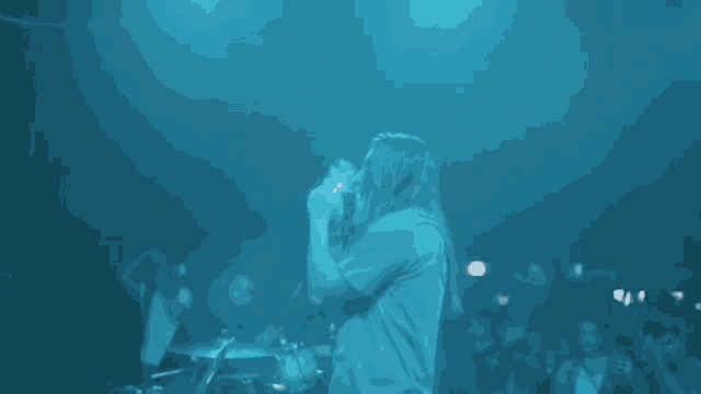 a man is singing into a microphone on stage in front of a crowd .