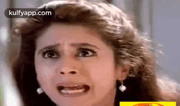 a woman is making a funny face with her mouth open and earrings .