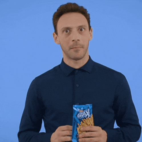 a man in a blue shirt is holding a bag of french fries and a toothpick