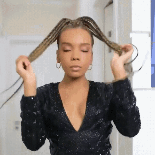 a woman in a black sequined dress is holding her hair in a ponytail
