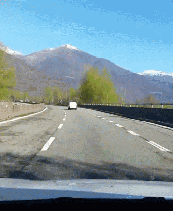 a white van is driving down a road with mountains in the background