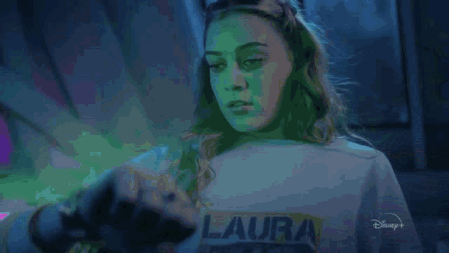 a woman in a laura sweatshirt is holding a mouse in her hands .