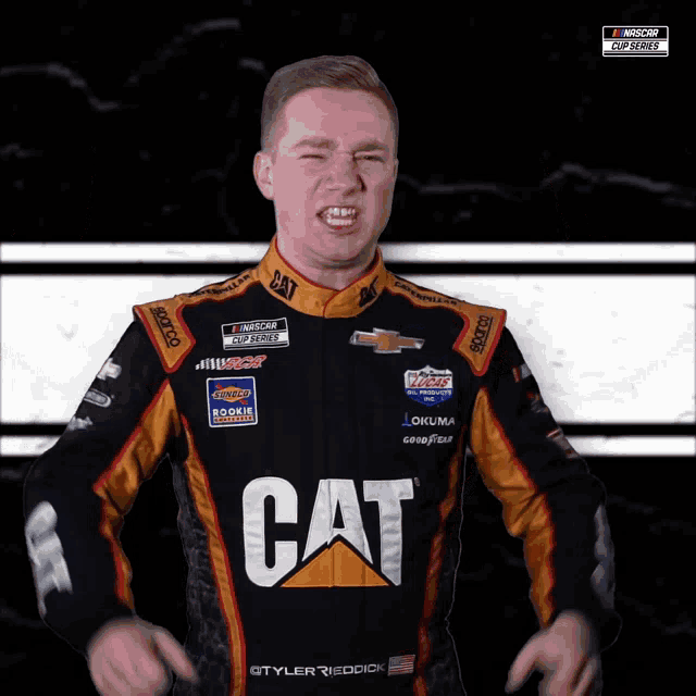a man wearing a cat racing suit holds his arms up in the air
