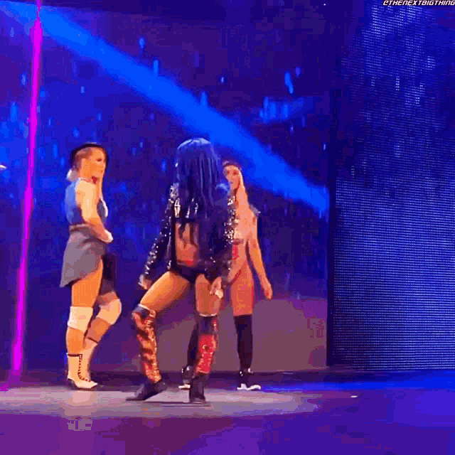 a group of women are standing on a stage dancing .