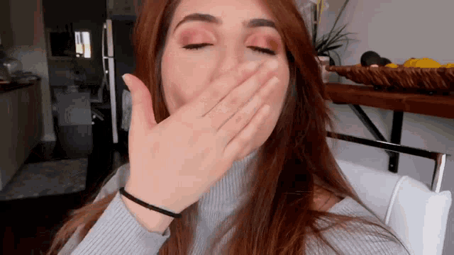 a woman covering her mouth with her hand in a living room