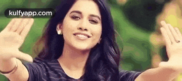 a woman is waving her hands in the air and smiling .