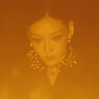 a close up of a woman 's face with a glowing orange background