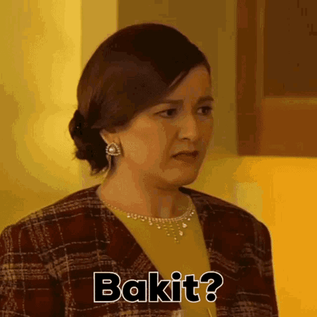 a woman wearing a plaid jacket and a yellow shirt is asking bakit