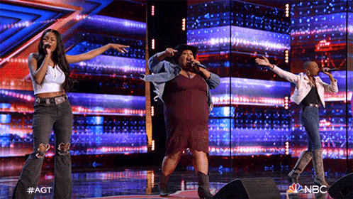 a group of women are singing on a stage in front of a large screen .