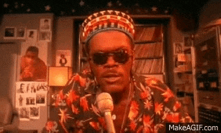 a man wearing a hat and sunglasses is talking into a microphone .