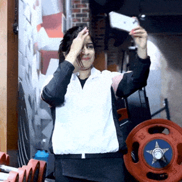 a woman taking a selfie in front of a barbell that says 20