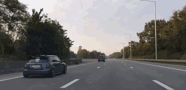 a blue mini cooper with a license plate that says nl - jzn - 331 is driving down the highway