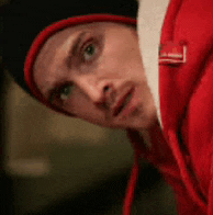 a man wearing a red hoodie and a black hat looks at the camera .