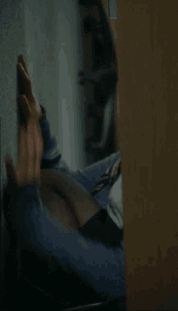 a woman leaning against a wall with her hand on her face