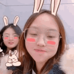 a girl wearing glasses and bunny ears is standing next to another girl wearing glasses and bunny ears .