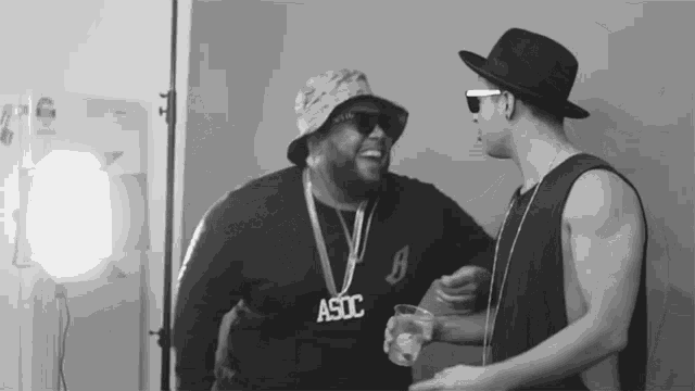 a man wearing a sweater that says a9dc talks to another man