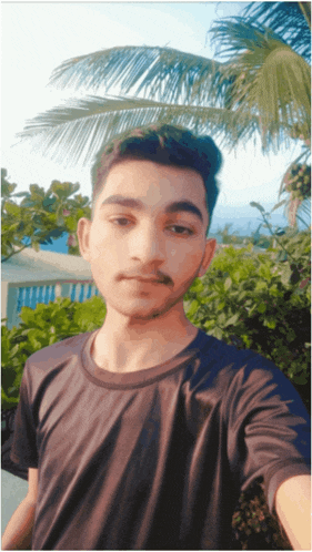 a young man in a black shirt takes a selfie in front of a palm tree