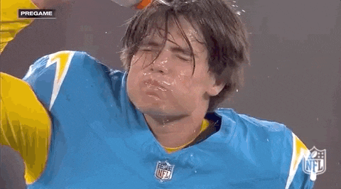 a man in a blue jersey with a lightning bolt on it is getting splashed with water .