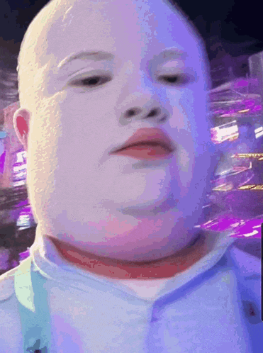 a close up of a baby 's face with purple lights in the background