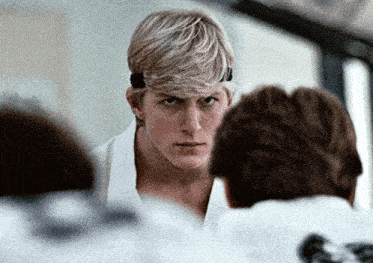 a man in a white karate uniform is looking at the camera