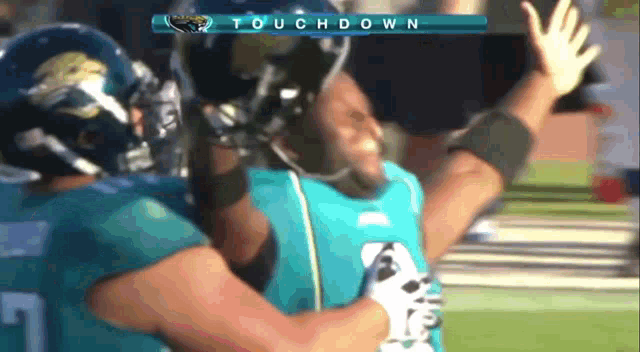 two football players celebrate a touchdown with a scoreboard behind them that says touchdown