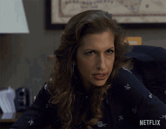 a woman sitting at a desk with a netflix logo on the bottom right