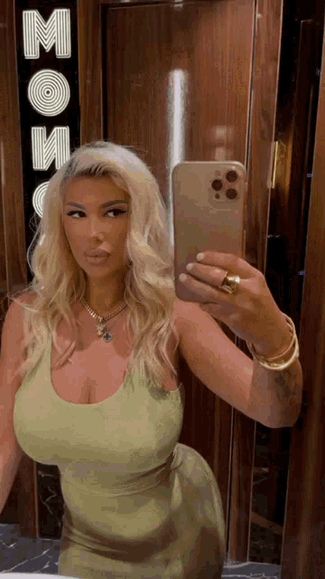 a woman in a green dress takes a selfie in front of a sign that says moose