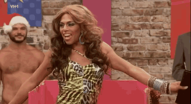 a woman in a leopard print dress is dancing in front of a brick wall while two men are standing behind her .