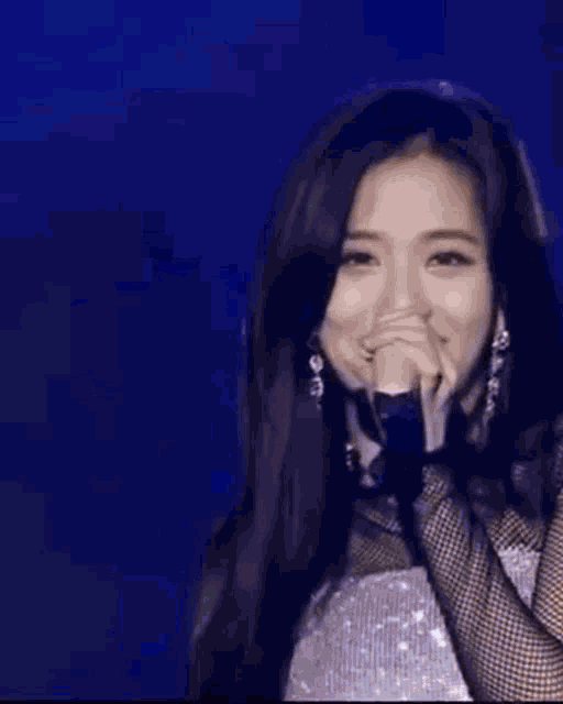 a woman in a crop top and shorts is dancing on a stage in front of a microphone .