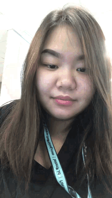 a woman wearing a lanyard that says ' bi ' on it looks at the camera