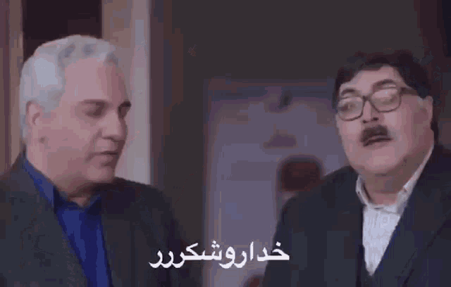 two men in suits and glasses are talking to each other in a room in a foreign language .
