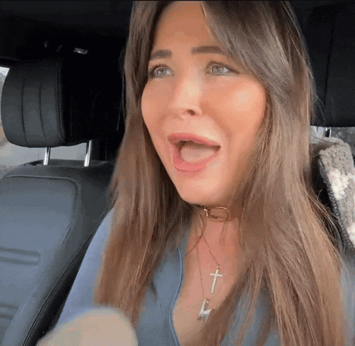 a woman is sitting in the back seat of a car with her mouth open