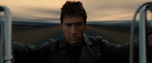 a man in a leather jacket stands in front of a railing with his arms outstretched