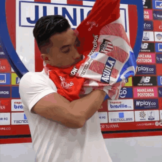 a man is holding a red and white shirt that says aguila