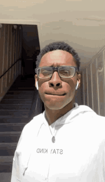 a man wearing glasses and a white shirt that says ' oiix ' on the front