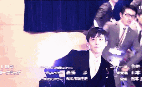a man in a suit and tie is standing in front of a blue curtain with the name warner on it