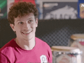 a man with curly hair wearing a red shirt is smiling .