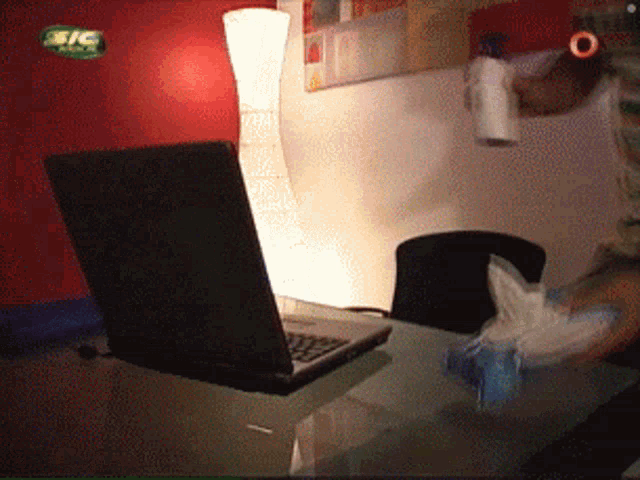 a laptop is on a desk with a bic logo on the wall