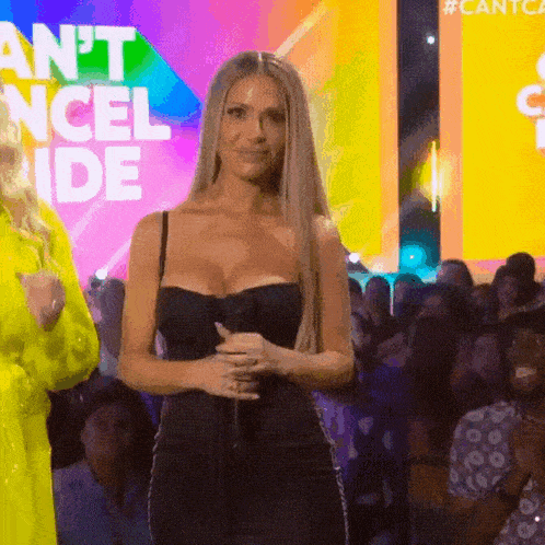 a woman in a black dress is standing in front of a crowd and a sign that says cantca