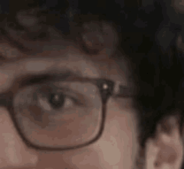a close up of a man wearing glasses with a beard .
