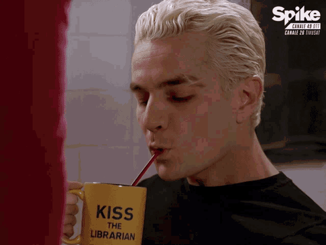 a man drinks from a yellow mug that says kiss the librarian
